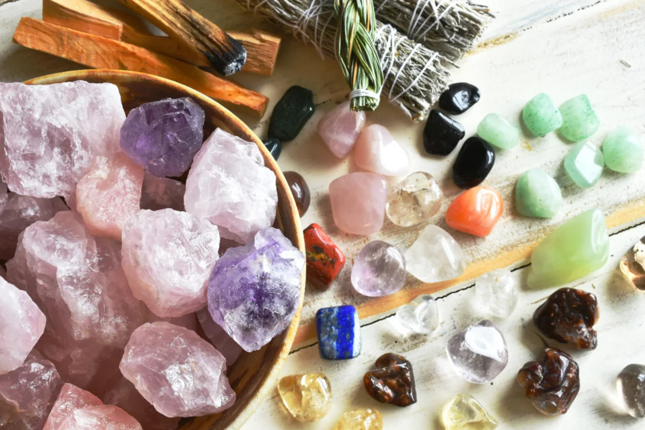 image of a bowl of rose quartz crystals for meditation with several other healing crystal and smudge sticks